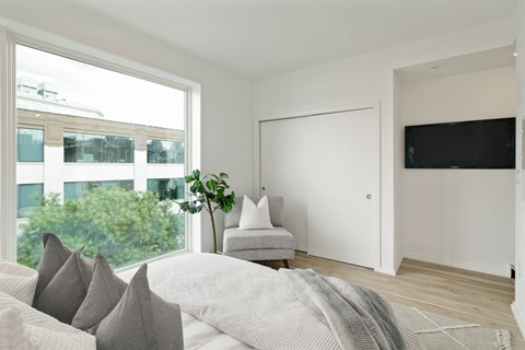 A living room with a white couch and a grey blanket.