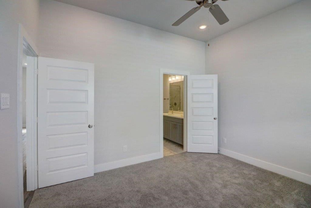 an empty bedroom with white doors and a ceiling fan