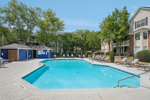 A large swimming pool surrounded by lounge chairs and trees.