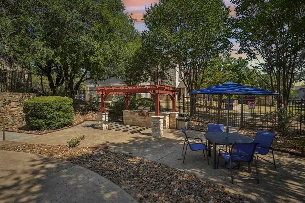 A red pavilion is surrounded by trees and chairs.