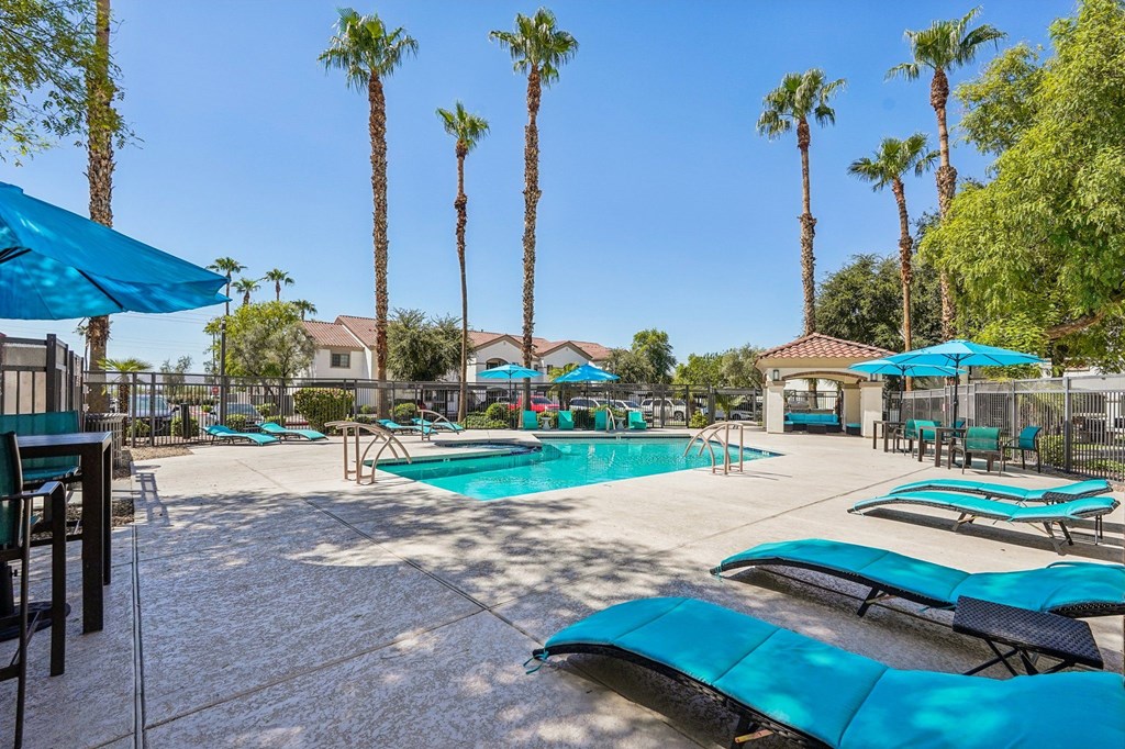 A pool surrounded by palm trees and blue umbrellas.