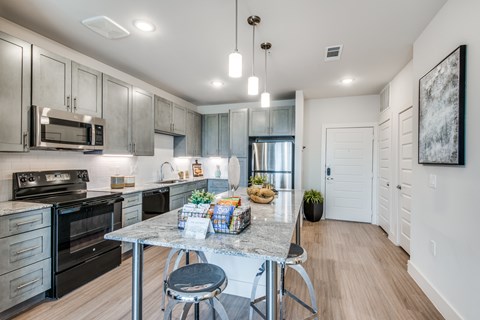 A modern kitchen with a table and chairs in the middle.