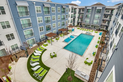 A large swimming pool surrounded by a grassy area and lounge chairs.