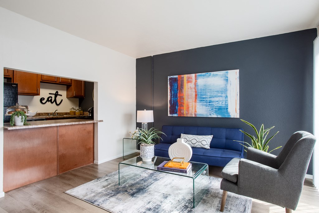 Living room with stylish wood-style flooring and view to breakfast bar at Midtown on Seneca, a pet-friendly apartment community near East Central Tucson, Tucson, AZ.