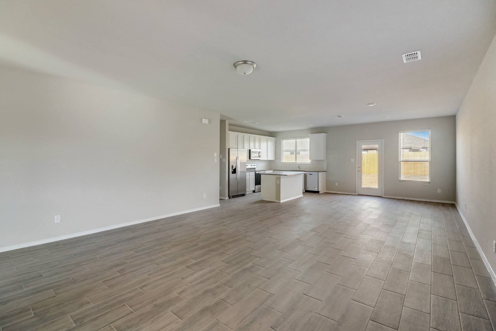 the living room and kitchen of an empty house with wood flooring