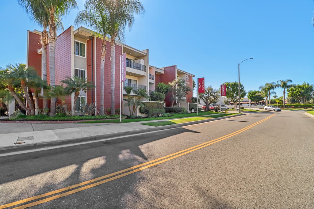 A street view of a residential area with apartment buildings and palm trees.