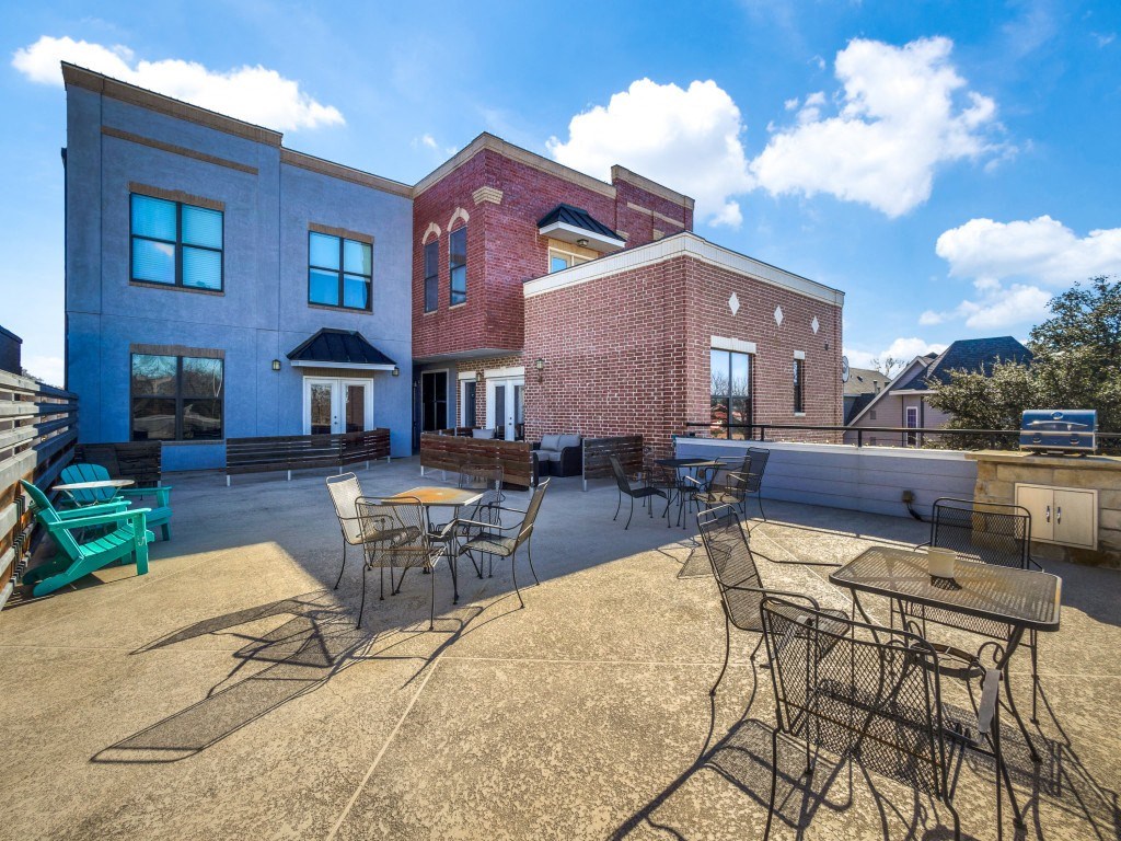 a patio with tables and chairs and a brick building in the background