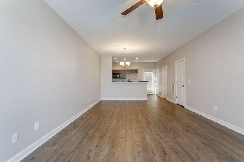 an empty living room and kitchen with a ceiling fan