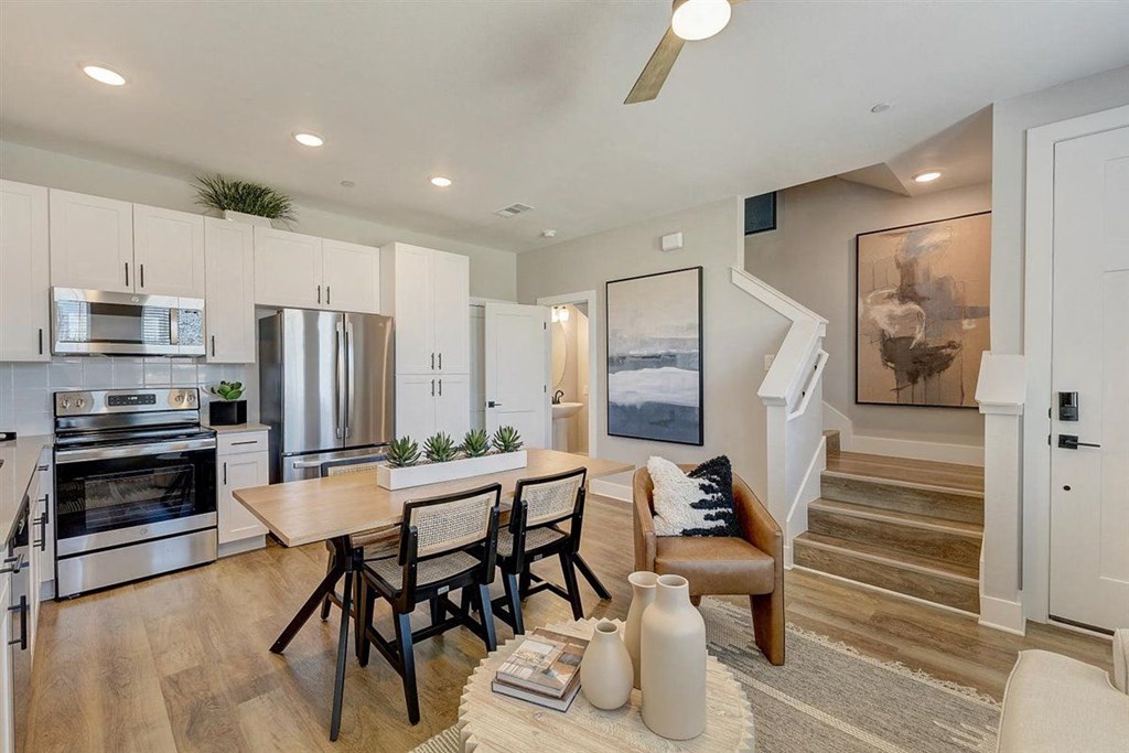 a kitchen and living room with a staircase in the background