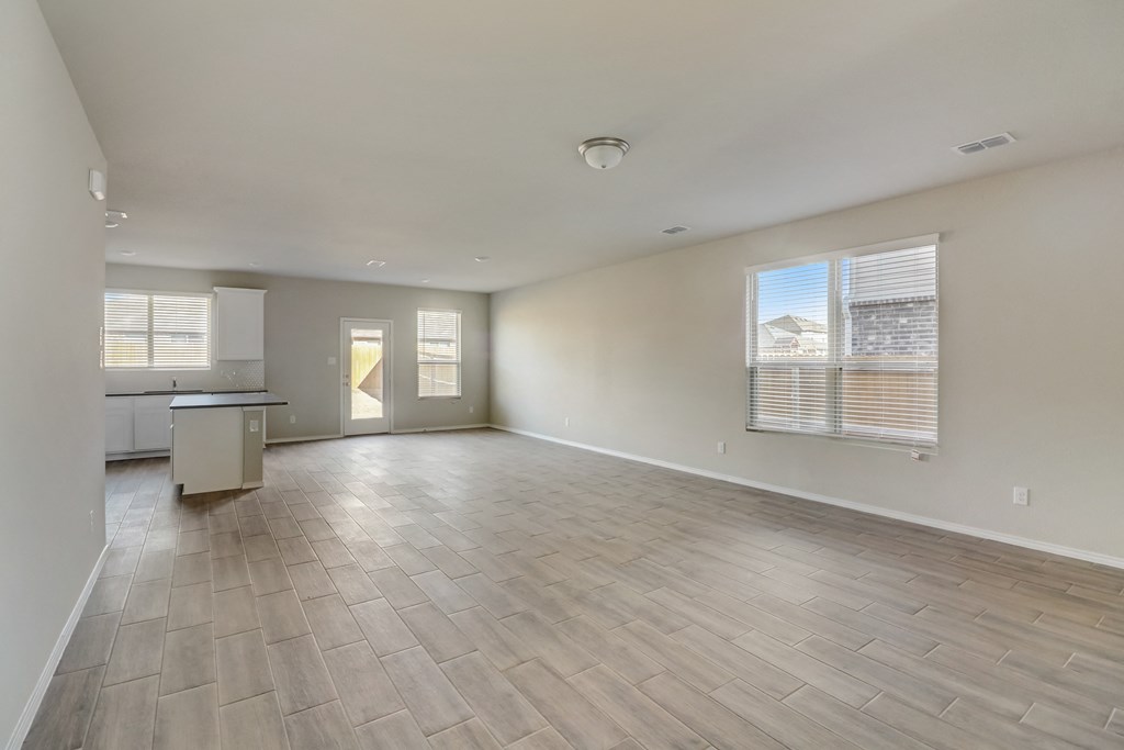 an empty living room with a kitchen and a large window
