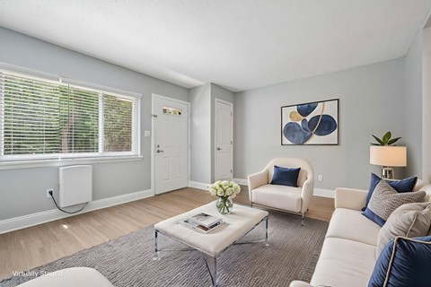 A living room with a white couch, a grey coffee table, and a painting on the wall.
