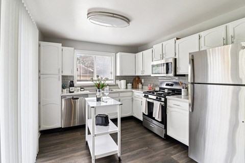 A kitchen with white cabinets and a black fridge.