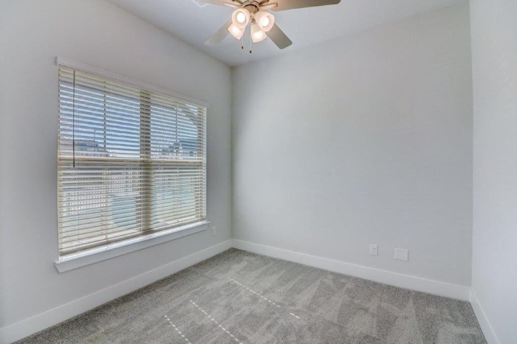 a bedroom with a large window and a ceiling fan