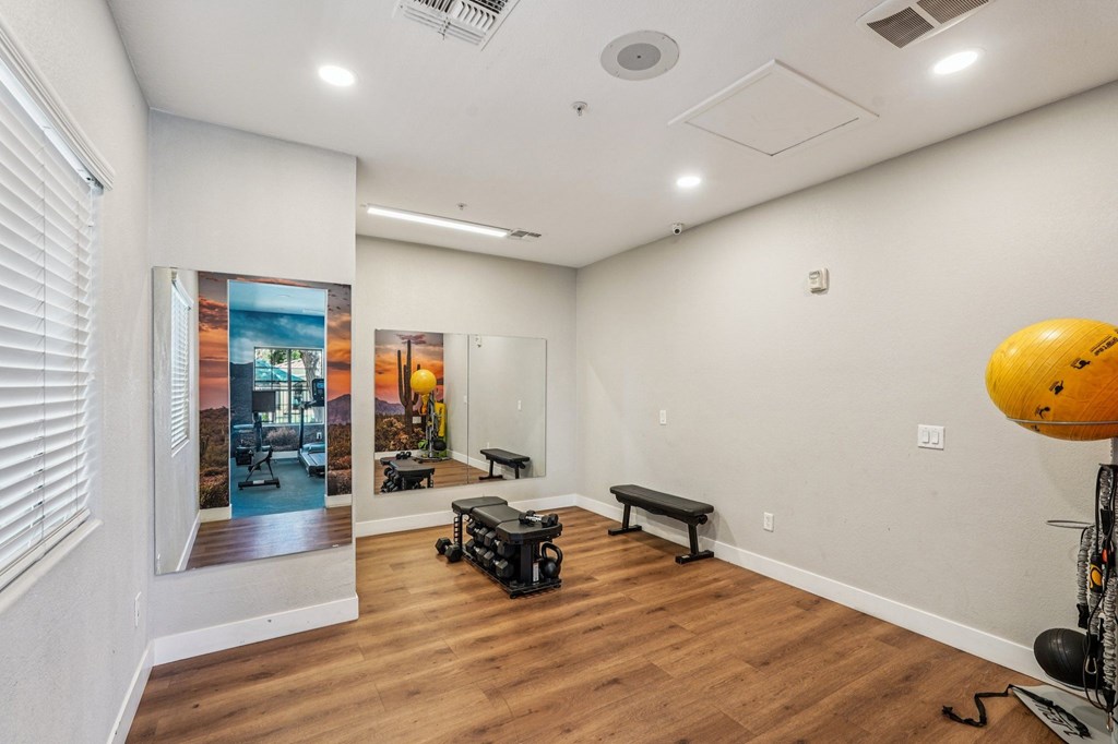 A room with a wooden floor and a wall with a picture of a sunset.