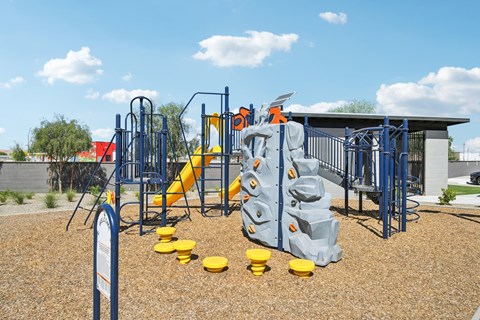 A playground with a blue and yellow slide and climbing structure.
