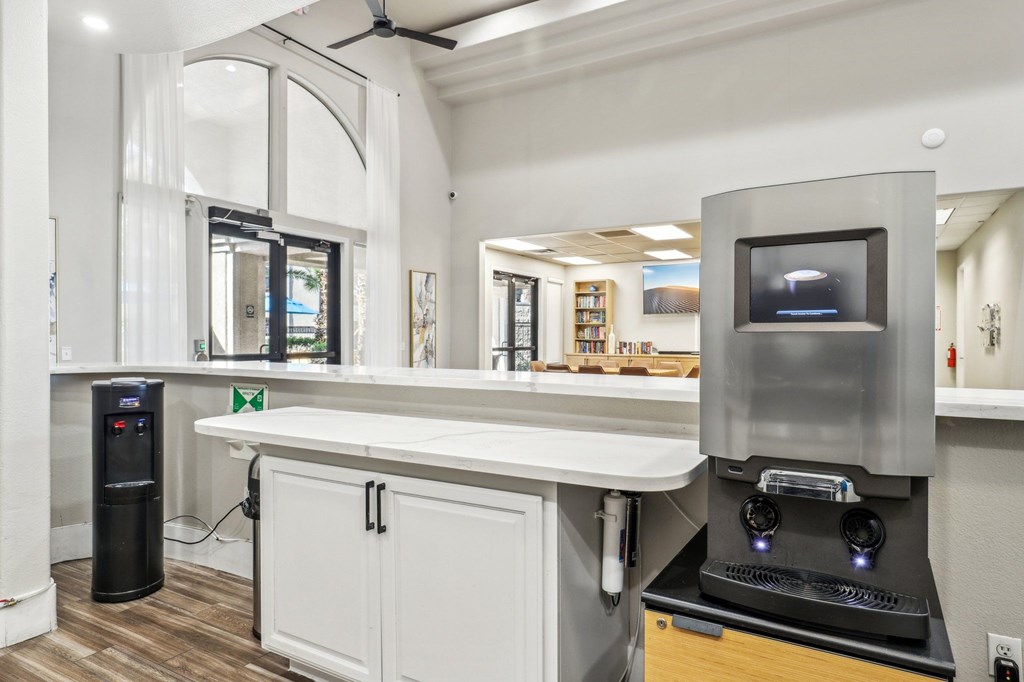 A modern kitchen with a black coffee machine and a white countertop.