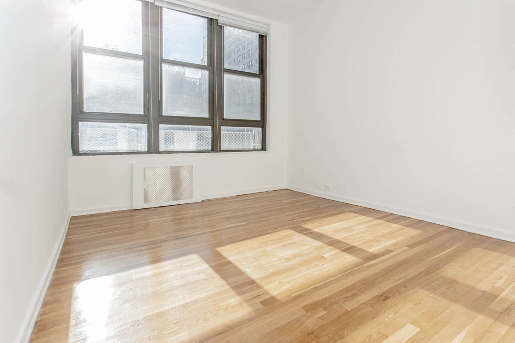 an empty room with a window and wooden floors