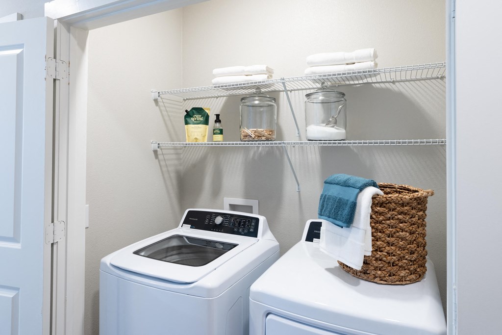 a small laundry room with a washer and dryer and a shelf above a