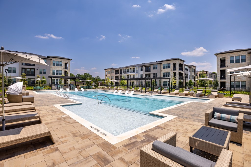 a swimming pool with lounge chairs and buildings in the background