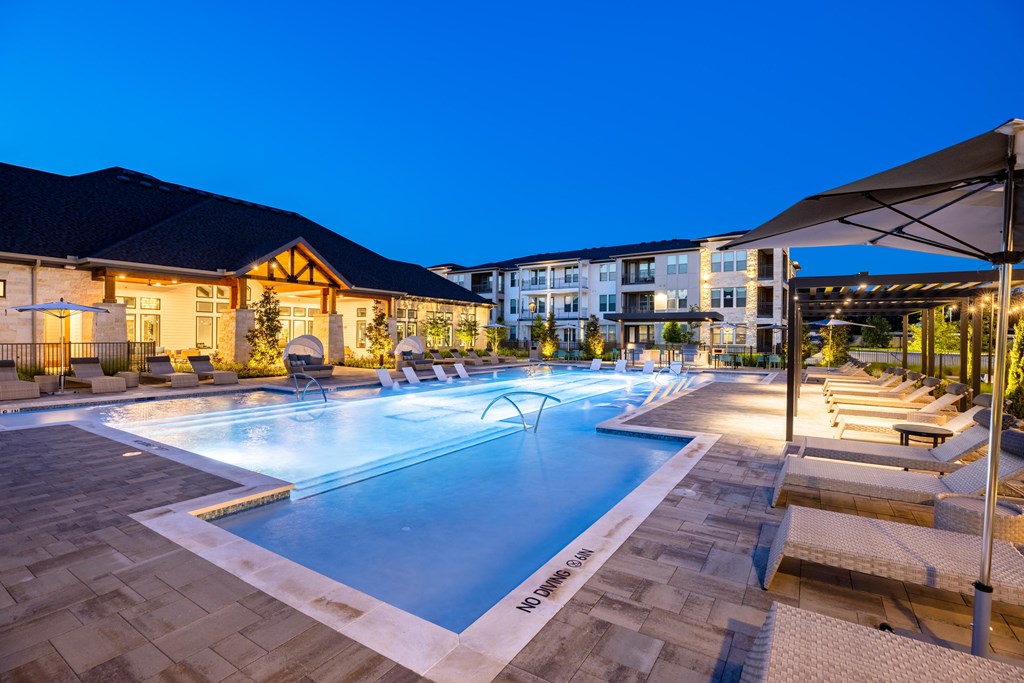 a swimming pool with seating around it at night