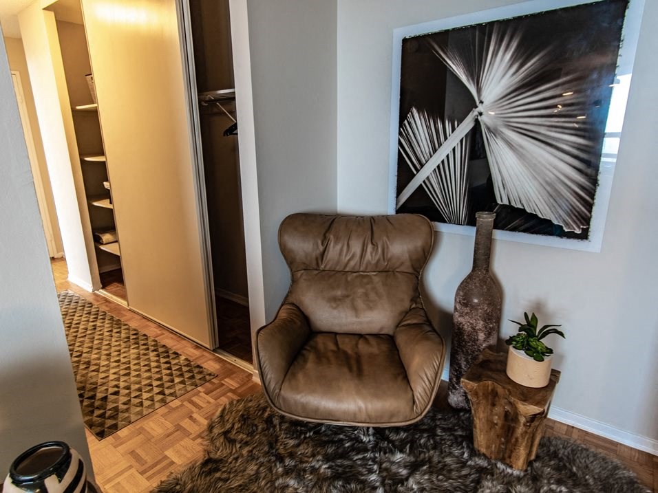 a living room with a brown leather chair and a painting on the wall