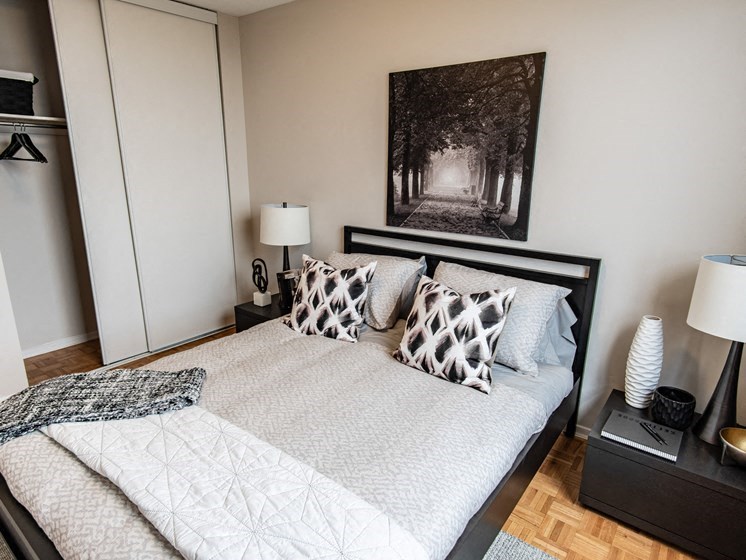 a bedroom with a bed with pillows and a picture of a forest