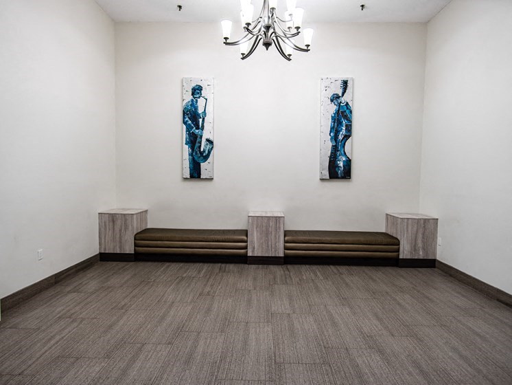 a room with benches and paintings on the wall and a chandelier