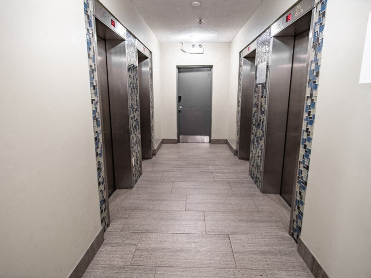a hallway with rows of elevators in a building