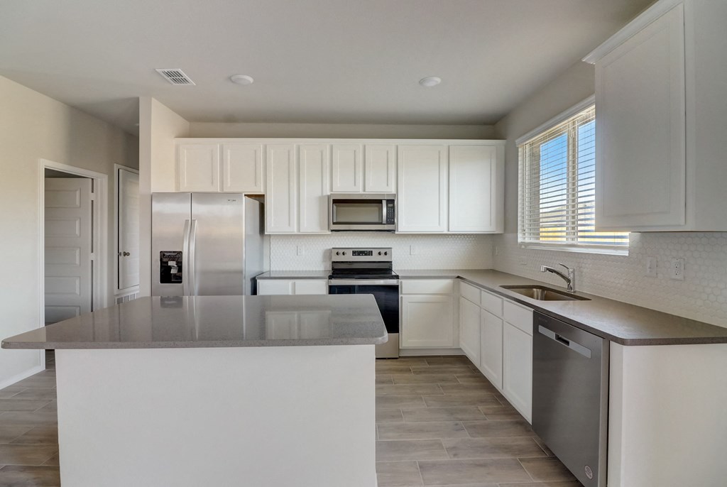 an empty kitchen with white cabinets and stainless steel appliances