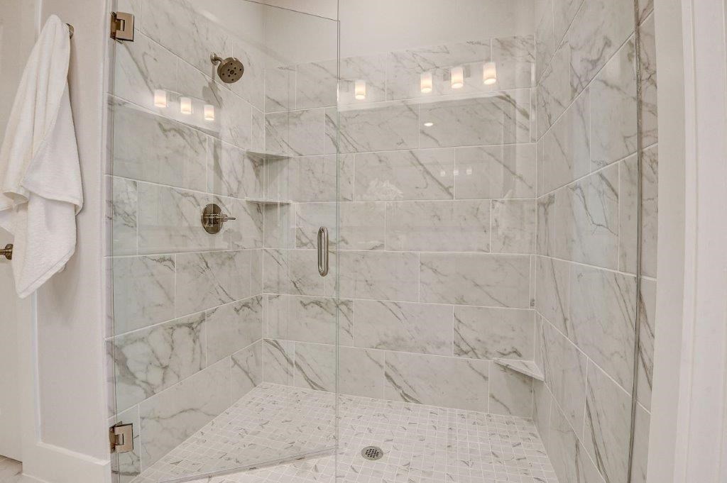 a bathroom with a tiled shower with a glass door
