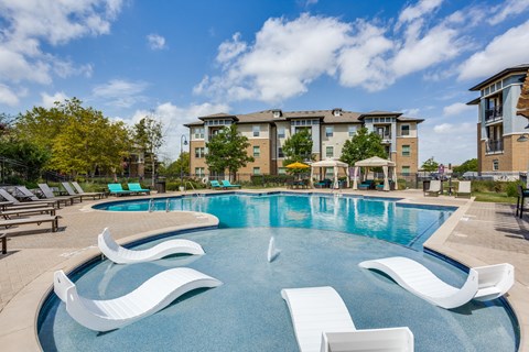 Resort-style swimming pool with in-water tanning loungers at 33hundred Apartments on Wells Branch Parkway Austin TX, offering luxury amenities and pet-friendly living