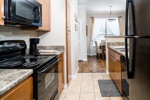 A kitchen with black appliances and wooden cabinets.