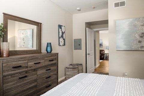 A bedroom with a large bed and a dresser with a mirror above it.