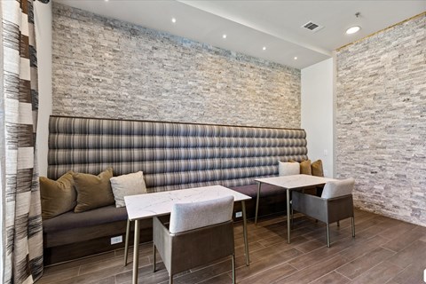 A dining area with a table and chairs in front of a grey couch.