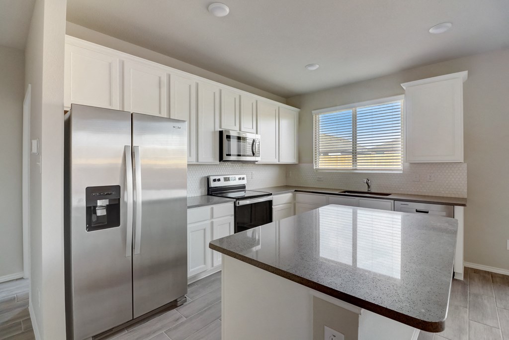 an empty kitchen with stainless steel appliances and white cabinets
