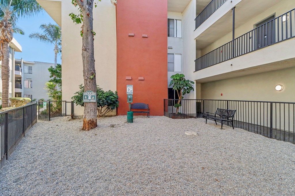 A courtyard with a red wall and a tree in the middle.