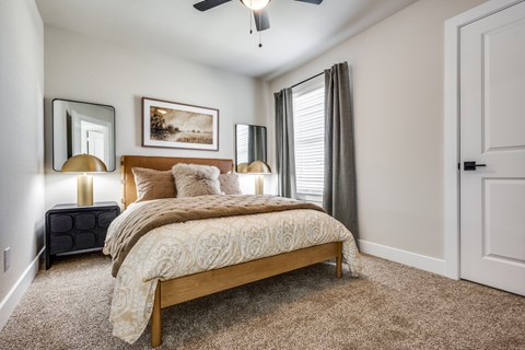A bedroom with a bed, two lamps, and a painting on the wall.