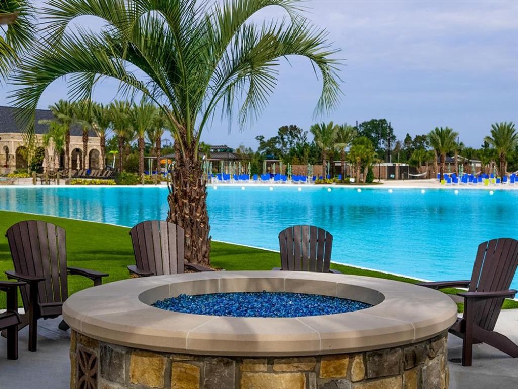 an outdoor jacuzzi with chairs and a palm tree in front of a pool