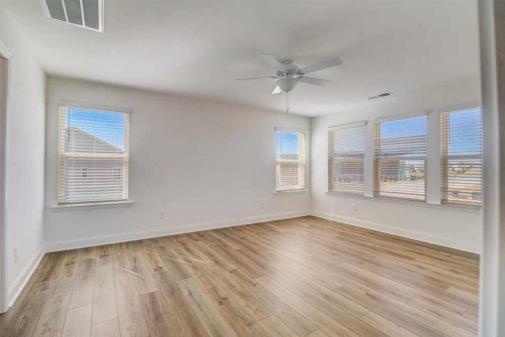 an empty bedroom with hardwood floors and a ceiling fan