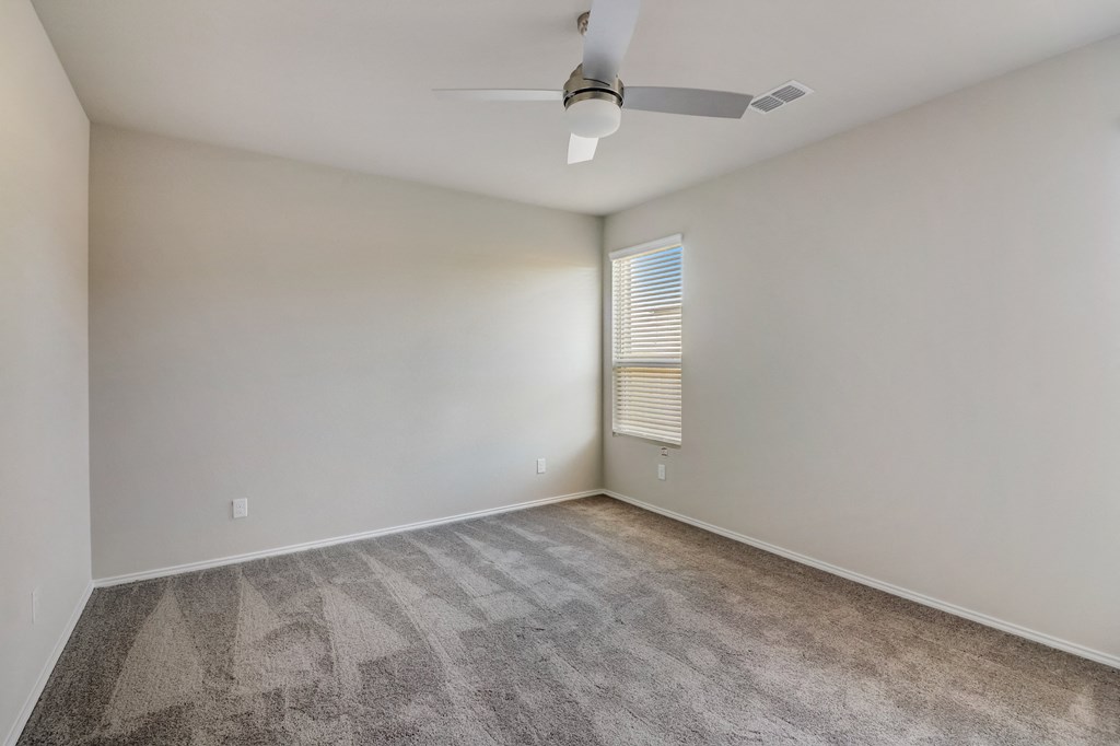 an empty living room with carpet and a ceiling fan