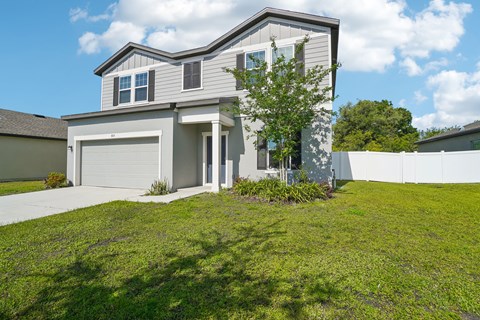 A house with a grey and white exterior and a large front yard.