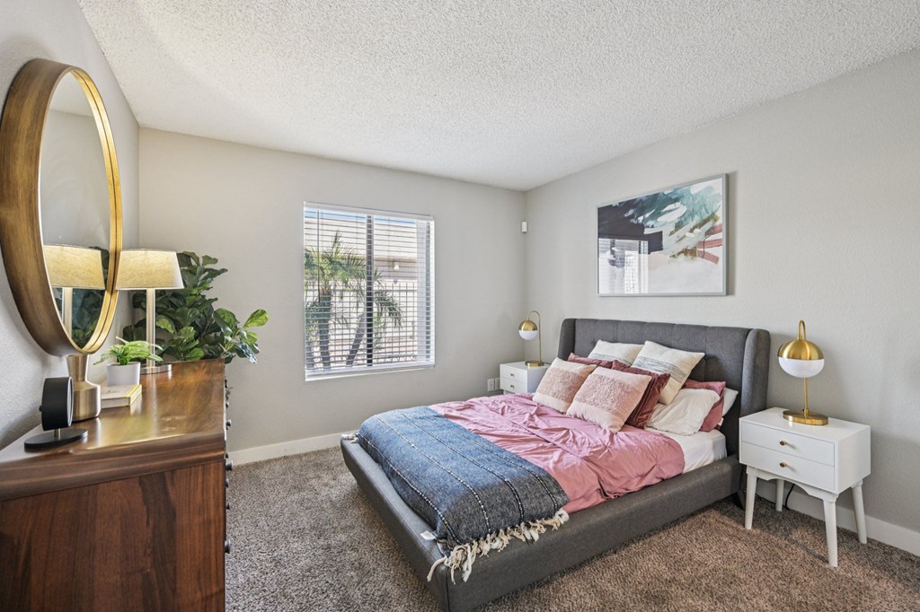 A bedroom with a bed, nightstand, and a mirror.