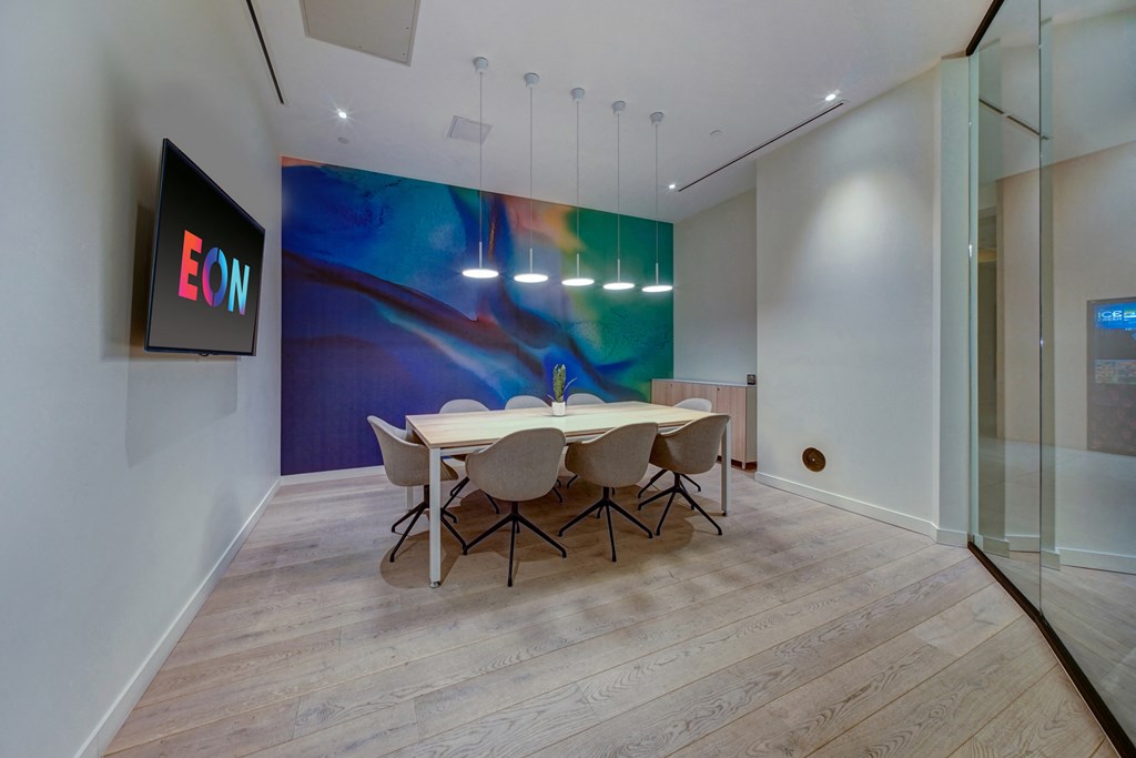 a conference room with a table and chairs and a large painting on the wall
