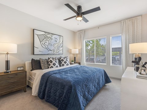 A bedroom with a bed, nightstand, and a ceiling fan.