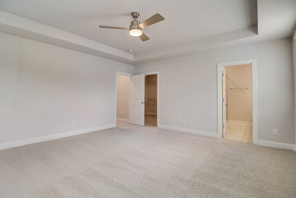 an empty bedroom with a ceiling fan