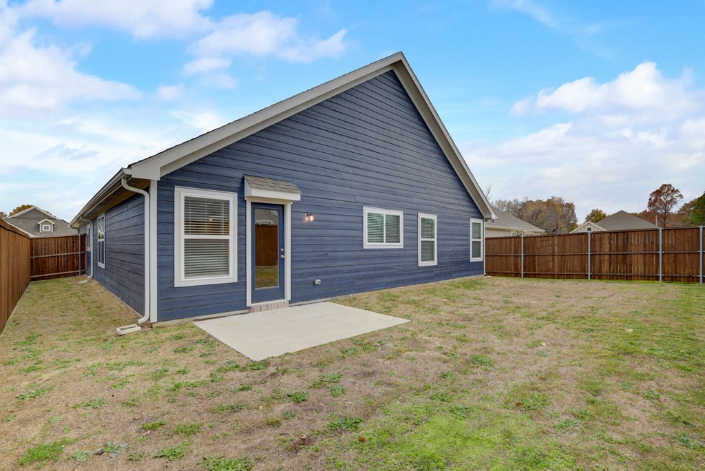the outside of a blue house with a yard and a wooden fence