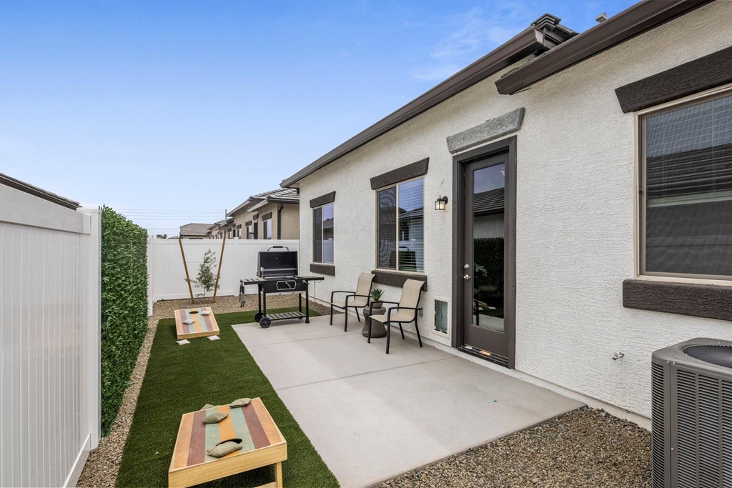 A patio with a table and chairs is surrounded by a white fence.
