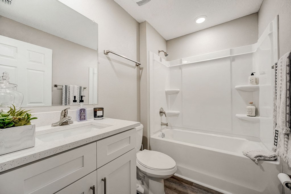 White bathroom with a tub, sink, and toilet at The Groves at Lake Ella in Lady Lake, Florida, a pet-friendly rental community.