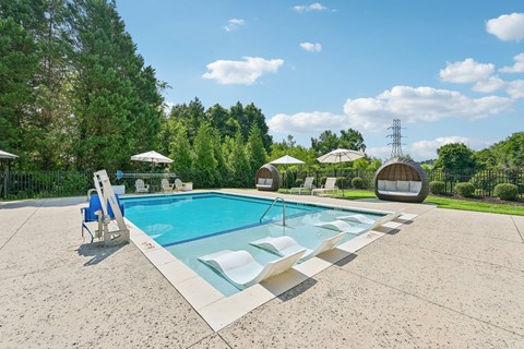 A large resort-style swimming pool at Hawks Landing in Hickory NC surrounded by trees and lounge chairs