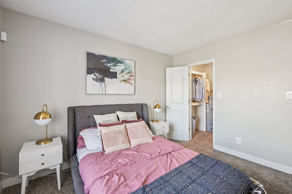 A bedroom with a bed, nightstand, and a painting on the wall.